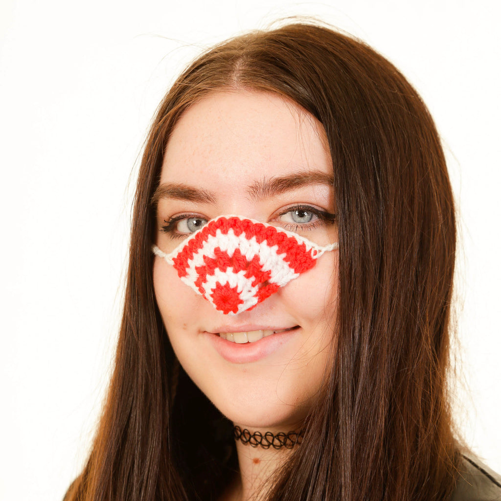 Person wearing a red and white nose warmer on a white background